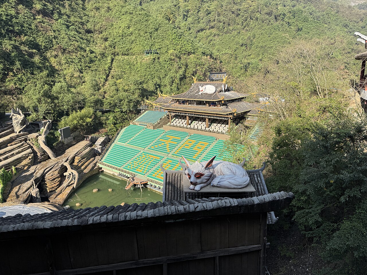 مسرح عرض الثعلبة الجنية الفعلي في وادي تيانمن، مع تمثال الثعلبة على السقف — The actual Tianmen Fox Fairy theatre in the valley, with the show's fox mascot on the roof